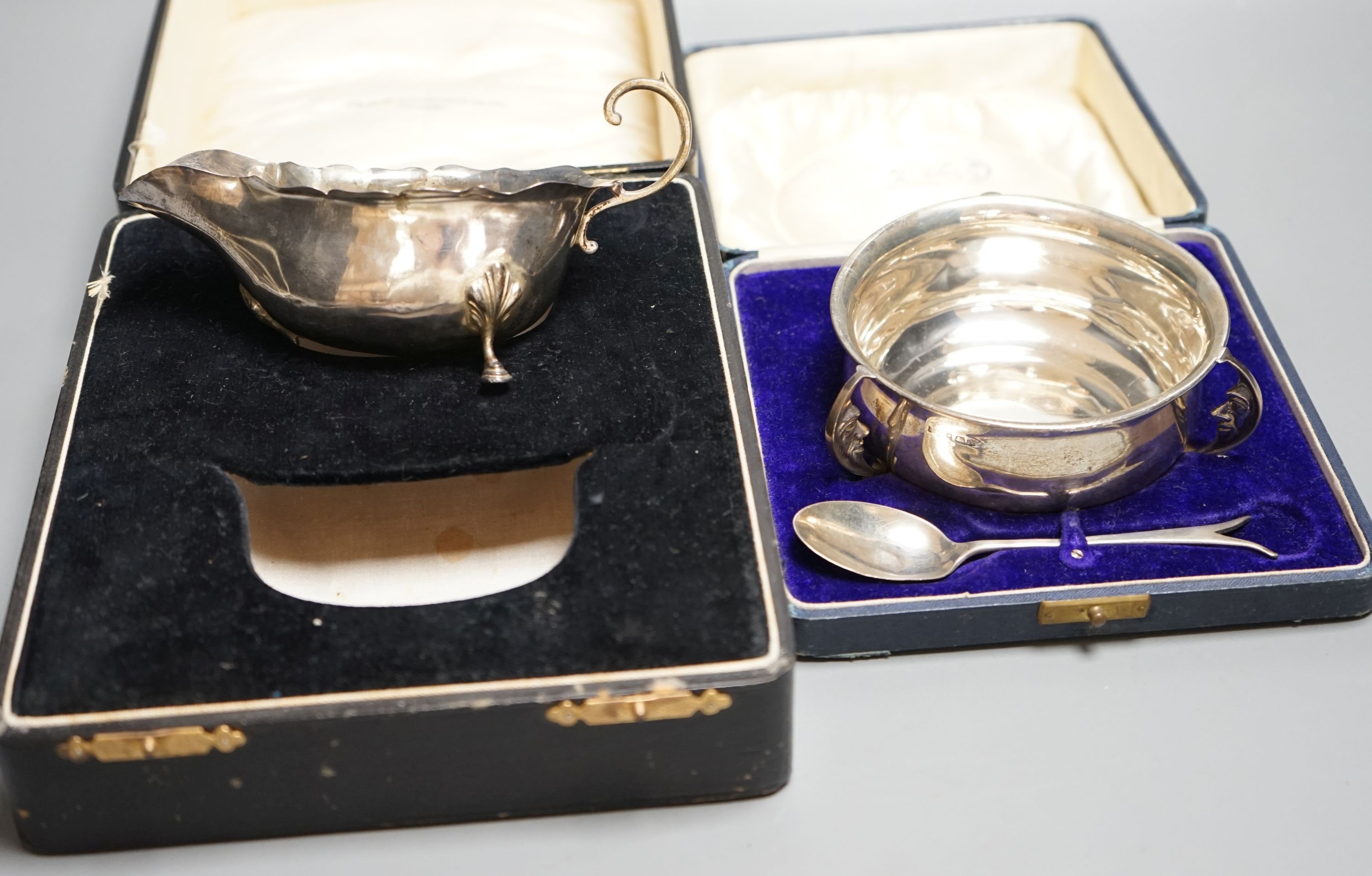 A cased George V silver three handle bowl and spoon, Birmingham, 1928 and a silver sauceboat, 7oz.
